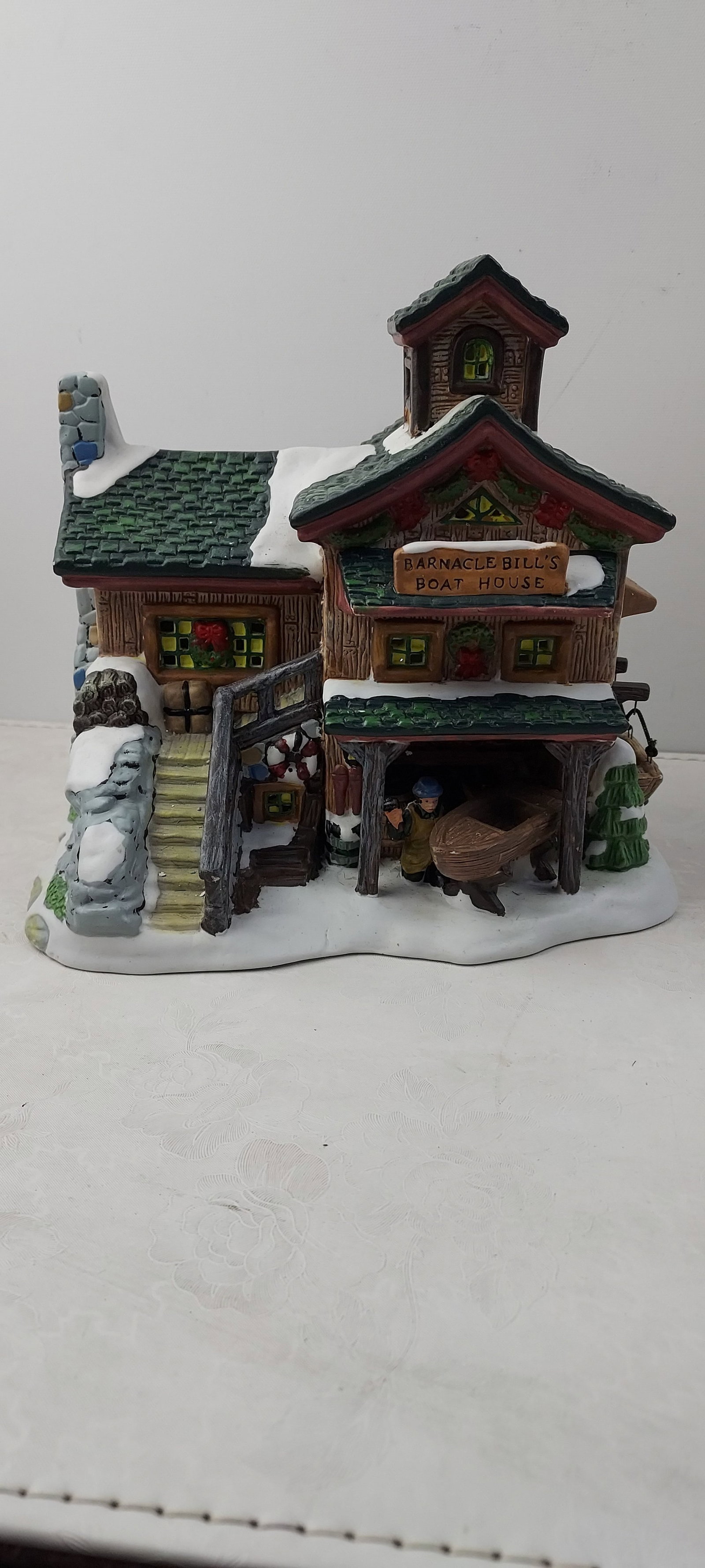 2003 Santa's Workbench Collection Christmas Village Towne Series Barnacle Bill's Boat House: A 2003 Santa's Workbench Collection Christmas Village Towne Series 'Barnacle Bill's Boat House' miniature display building. This loose ceramic or porcelain piece depicts a heavily snow-dusted, multi-l