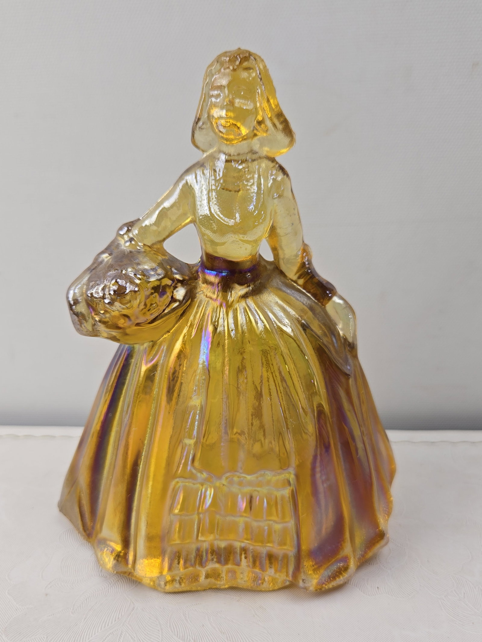 Vintage Wheaton Amber Carnival Glass Southern Belle Lady Figurine: This vintage Wheaton Amber Carnival Glass Southern Belle Lady Figurine depicts a standing lady in a long, full period dress, holding a basket of what appears to be flowers or fruit. The figurine is co