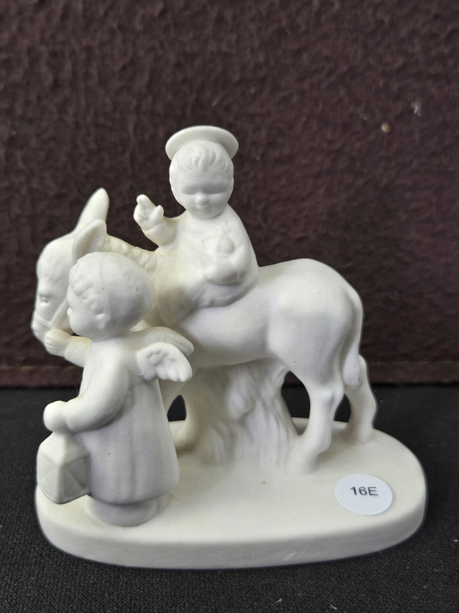 Vintage Goebel W. Germany White Bisque Porcelain Angel Leading Baby Jesus on Donkey Figurine HX334: A vintage Goebel W. Germany white bisque porcelain figurine, model number HX334, depicting an angel leading Baby Jesus on a donkey. The unpainted, matte, unglazed bisque figurine portrays a haloed fig