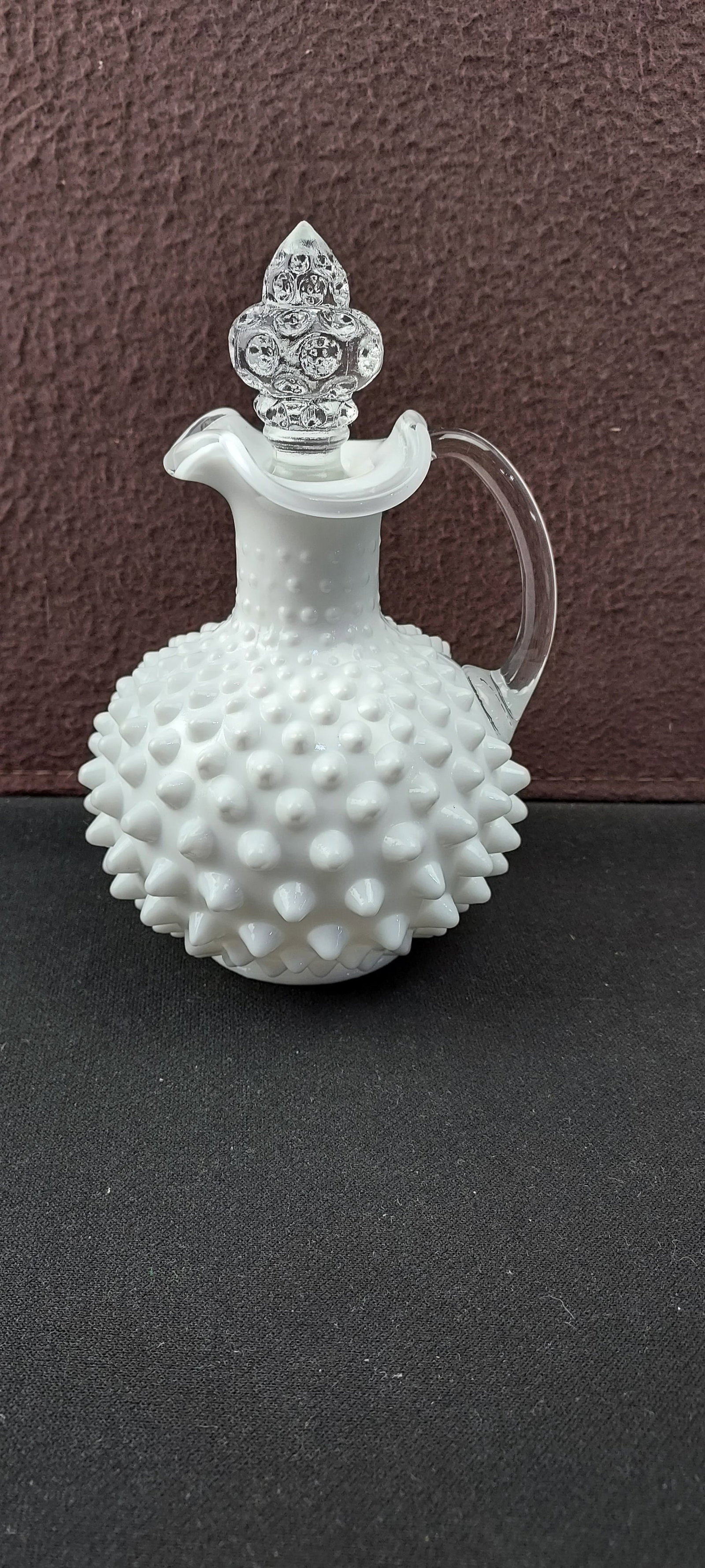 Vintage Fenton White Milk Glass Hobnail Cruet with Stopper: This charming vintage cruet, attributed to the Fenton Art Glass Company, features a bulbous body adorned with the distinctive hobnail pattern, crafted from white opalescent milk glass. It is fitted wi
