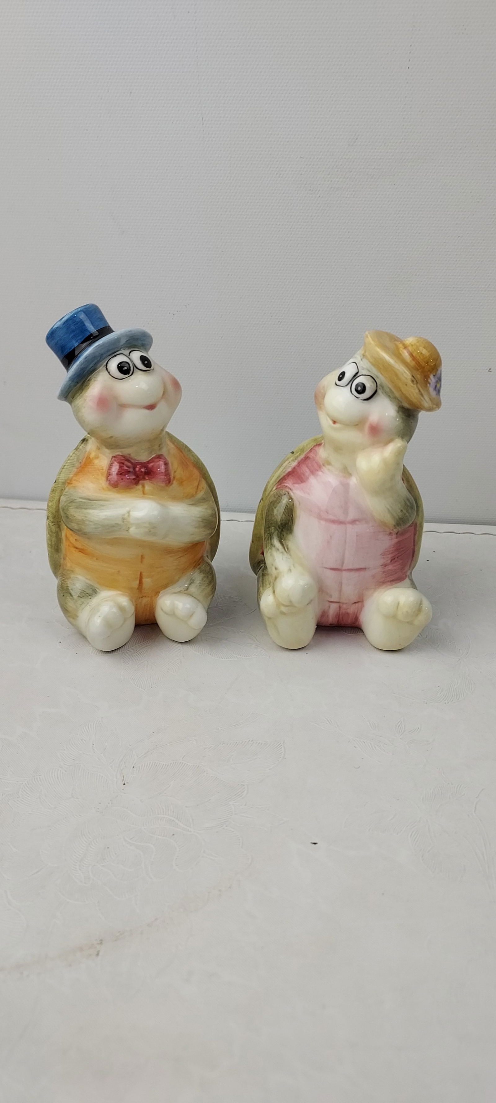 Vintage Homco Anthropomorphic Turtles: Vintage ceramic salt and pepper shakers, identified as Homco based on visual and web intelligence consensus, features two anthropomorphic turtles. One turtle is depicted wearing a blue top hat and a r