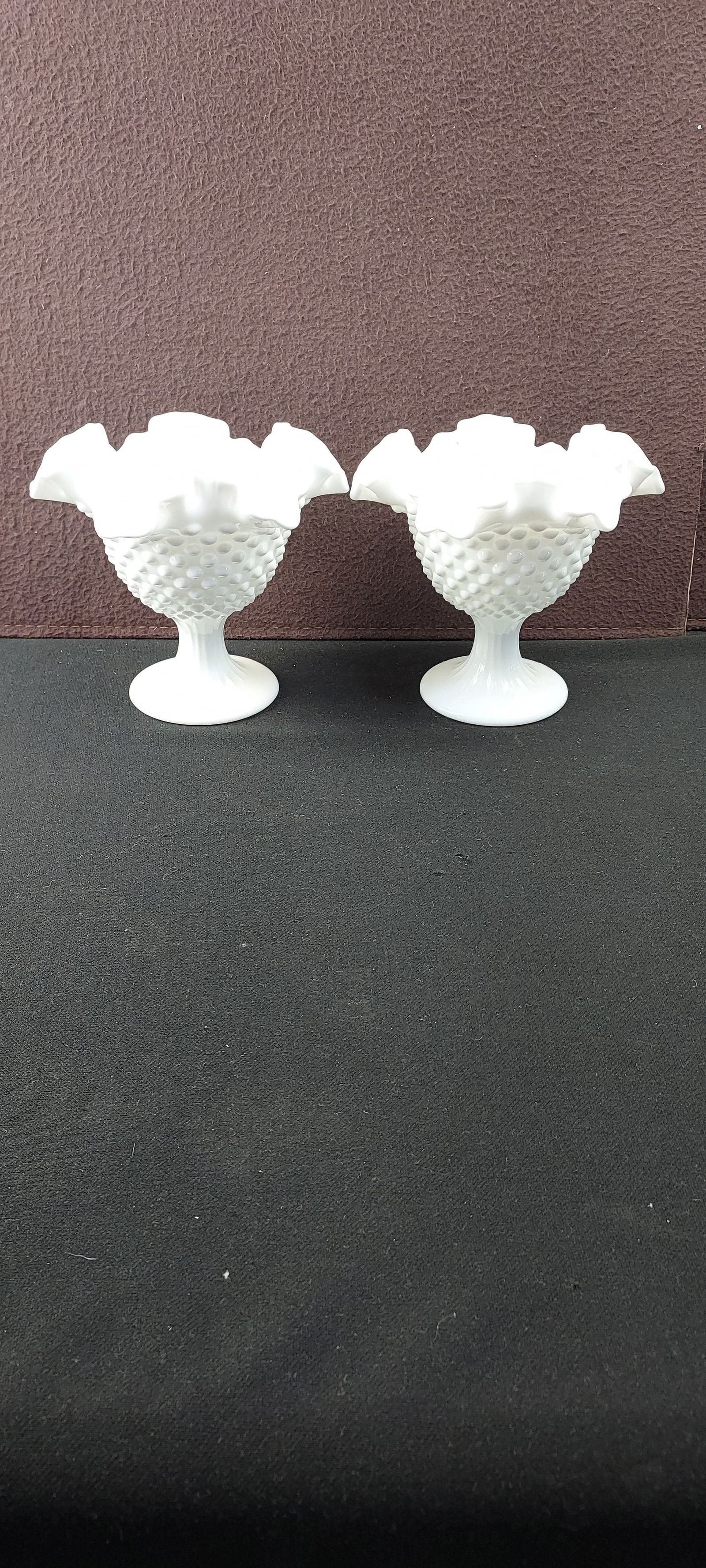 A Pair of Vintage Fenton White Hobnail Ruffled Milk Glass 5 1/2" Candleholders: A pair of vintage pedestaled decorative bowls, crafted from opaque white milk glass by Fenton. Each piece features a distinct hobnail or button pattern covering the exterior of its bowl, which is topp