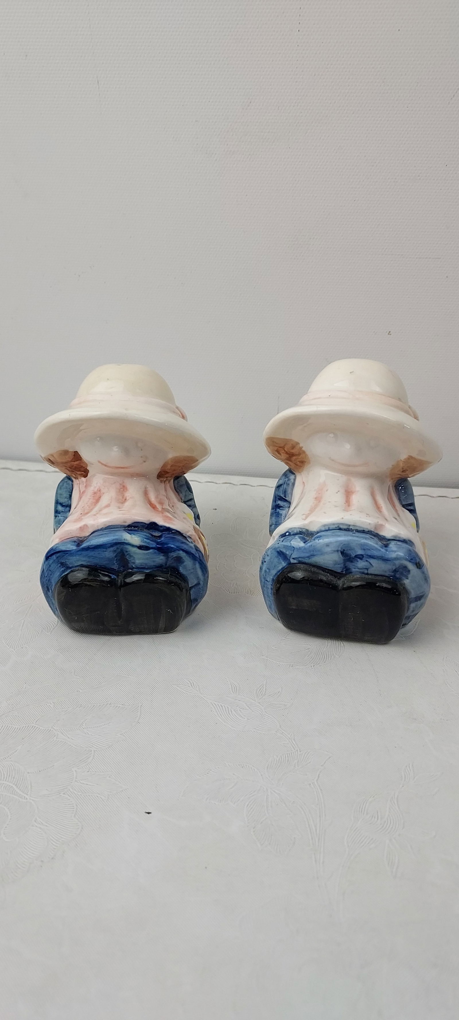 Vintage Holly Hobbie Ceramic Prairie Girls Salt and Pepper Shakers: A pair of vintage ceramic salt and pepper shakers, depicting two identical stylized figures, widely identified as 'Prairie Girls' from the Holly Hobbie aesthetic. Each figure is dressed in a wide-brim