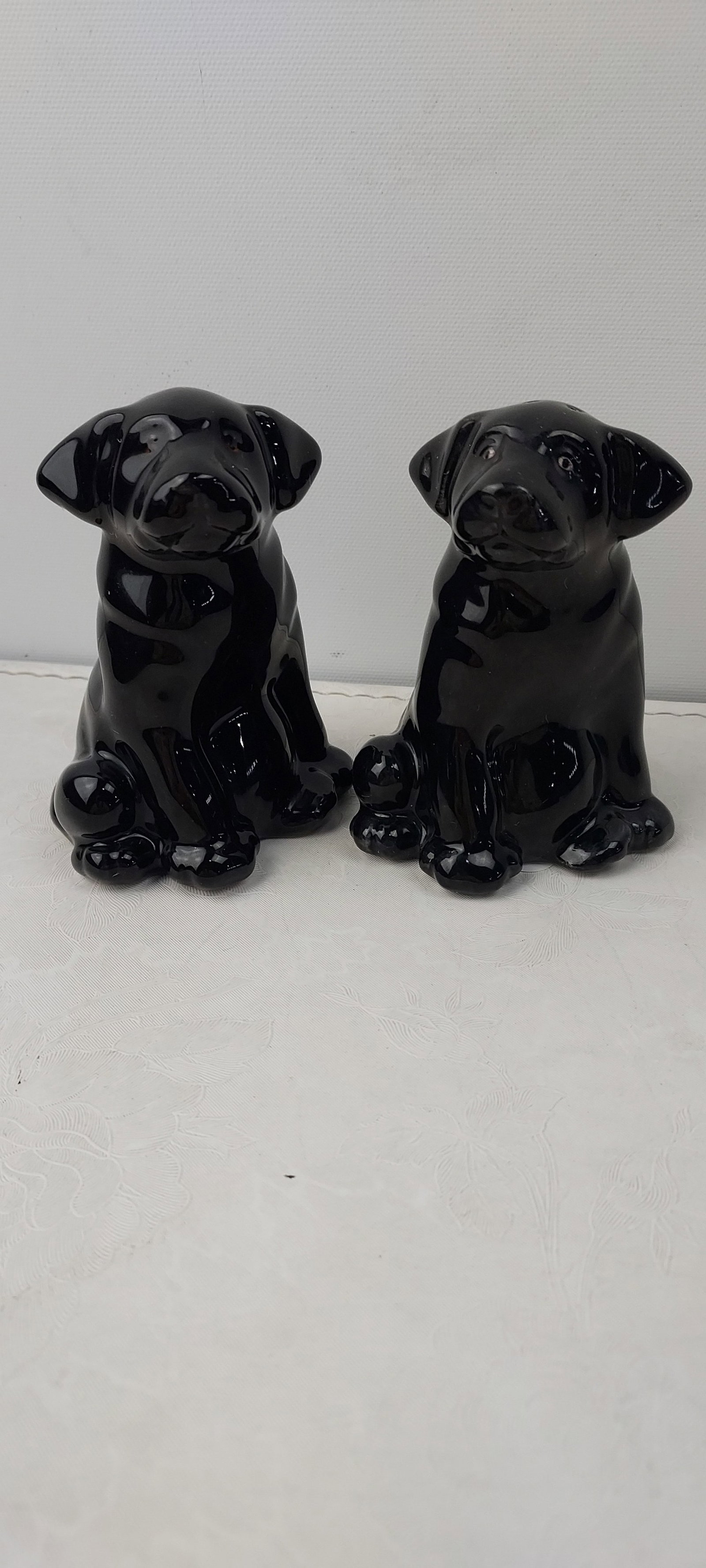 Ceramic Black Labrador Dog Salt and Pepper Shakers: A matching pair of ceramic black Labrador dog salt and pepper shakers. Each figurine depicts a sitting puppy with a glossy, highly reflective black glazed finish. Designed for functional use, each fea