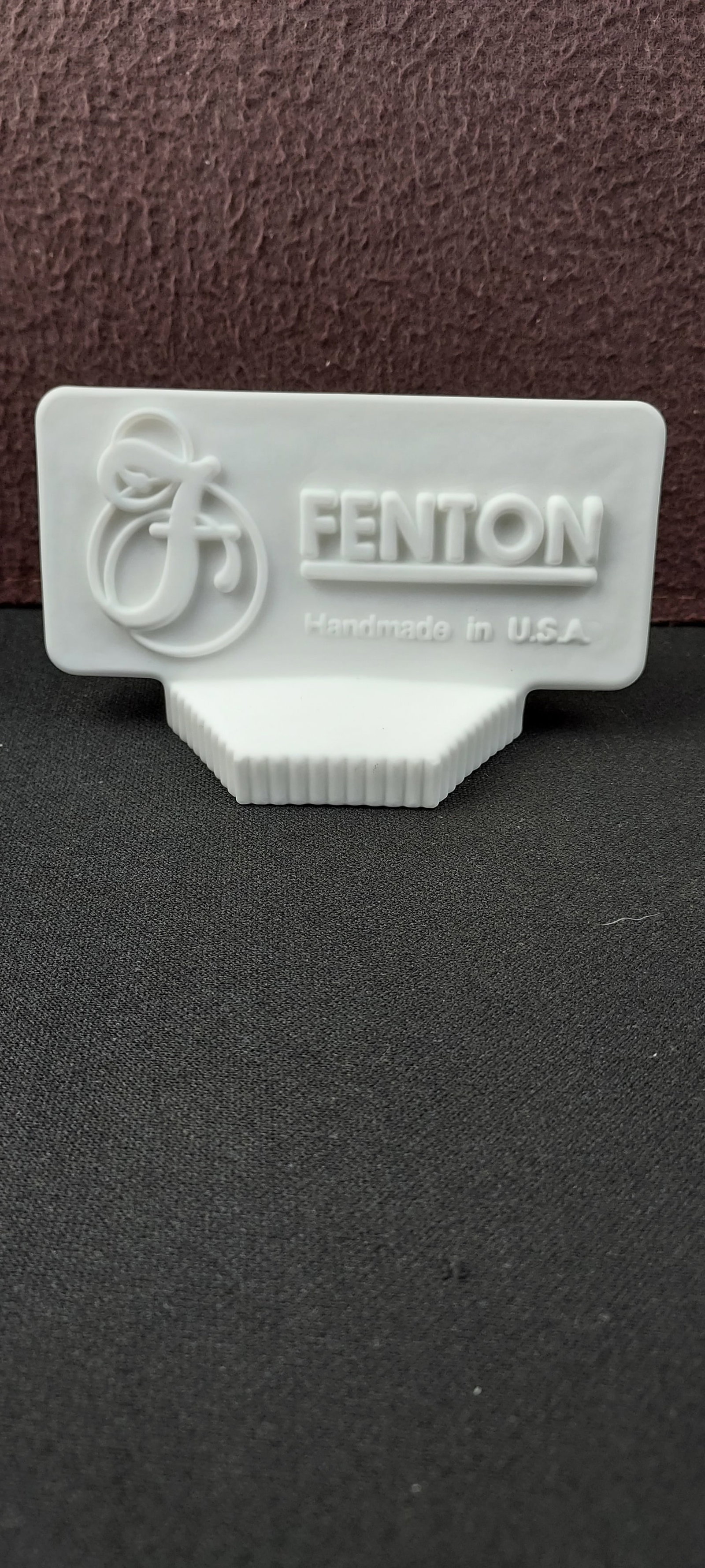 White Fenton Art Glass Dealer Logo Sign: A vintage Fenton Art Glass Dealer Logo Sign, a solid molded glass display piece. The rectangular top section features a stylized "F" logo alongside the embossed text "FENTON" and "Handmade in U.S.A."