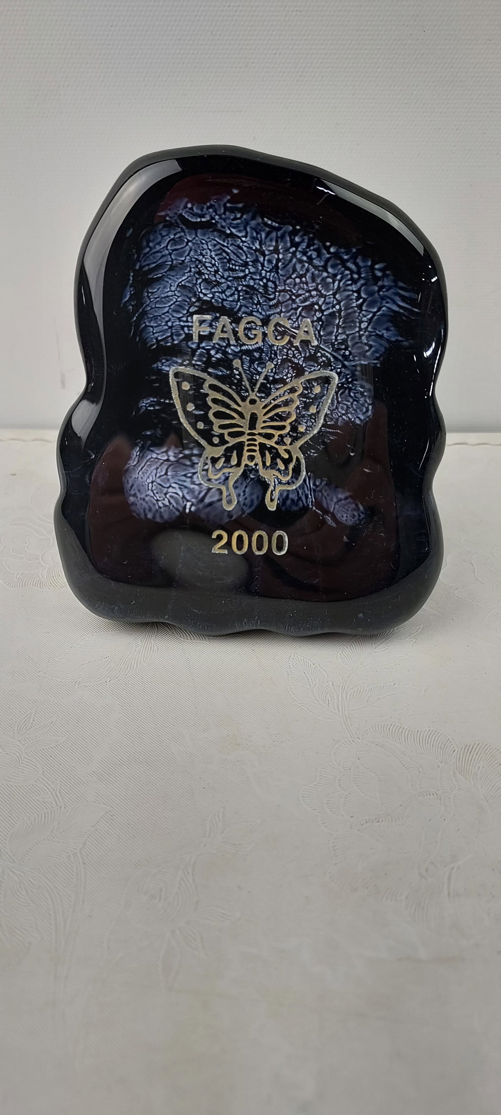 2000 Fenton Art Glass FAGCA 95th Anniversary Commemorative Butterfly Paperweight: This lot features a 2000 Fenton Art Glass FAGCA (Fenton Art Glass Collectors of America) 95th Anniversary Commemorative Butterfly Paperweight. The irregularly shaped decorative art glass piece is craf