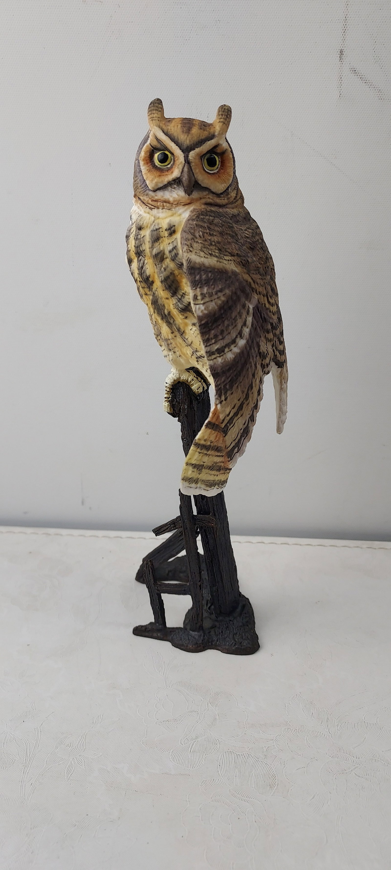 Hand-Painted Realistic Great Horned Owl Figurine on Branch Base: This loose, hand-painted figurine depicts a realistic Great Horned Owl, identifiable by its prominent ear tufts and characteristic plumage. The owl is sculpted perched upon a dark brown base, designed