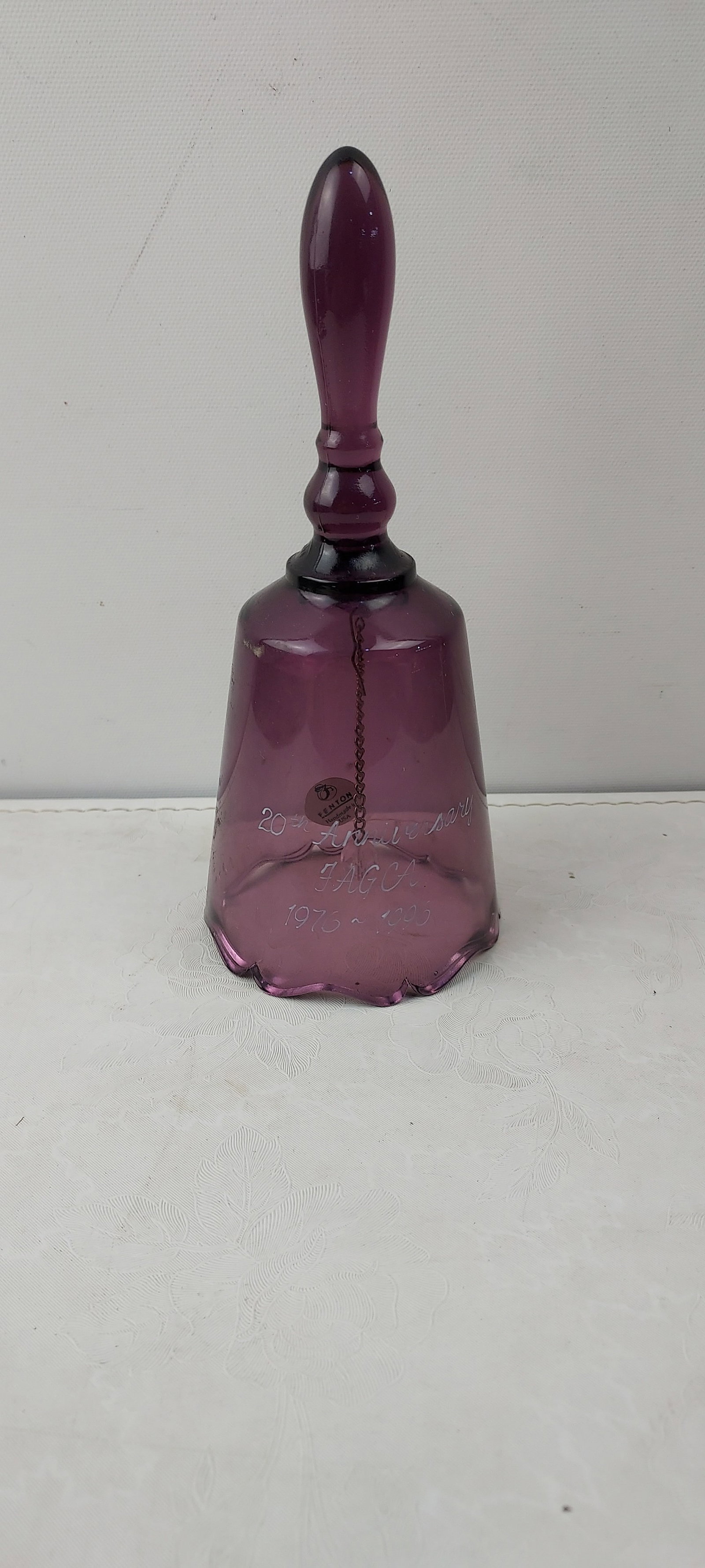 1996 Fenton Amethyst Glass Bell 20th Anniversary JAGCA 1976-1996: This is a commemorative amethyst-colored glass bell manufactured by Fenton, celebrating the "20th Anniversary JAGCA 1976 ~ 1996." The bell features etched script on its body detailing the anniversary.