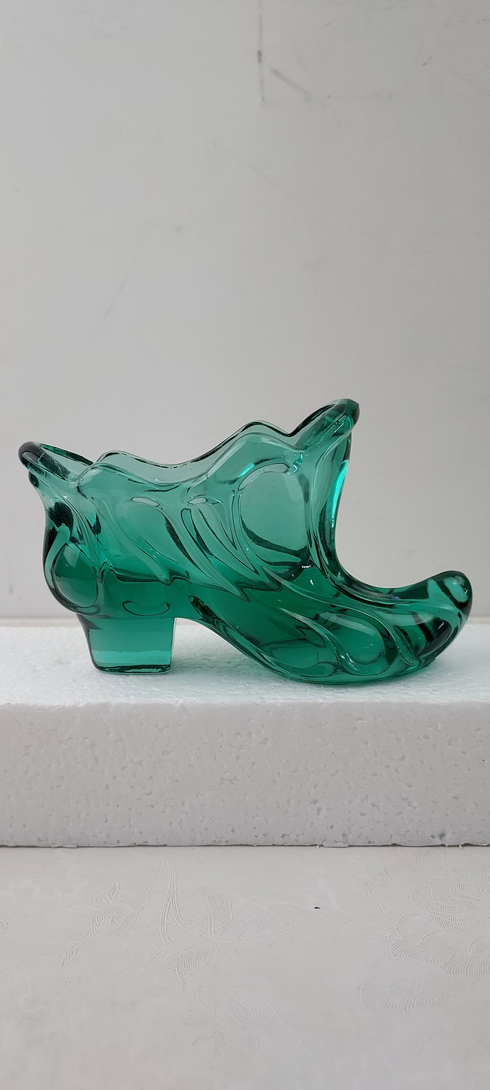 Vintage Fenton Teal-Green Molded Glass Buckle Slipper Shoe: This vintage decorative piece is a Fenton Art Glass molded slipper shoe, crafted from translucent teal-green glass. It features a prominent ruffled or wavy top edge and distinctive swirling relief pat