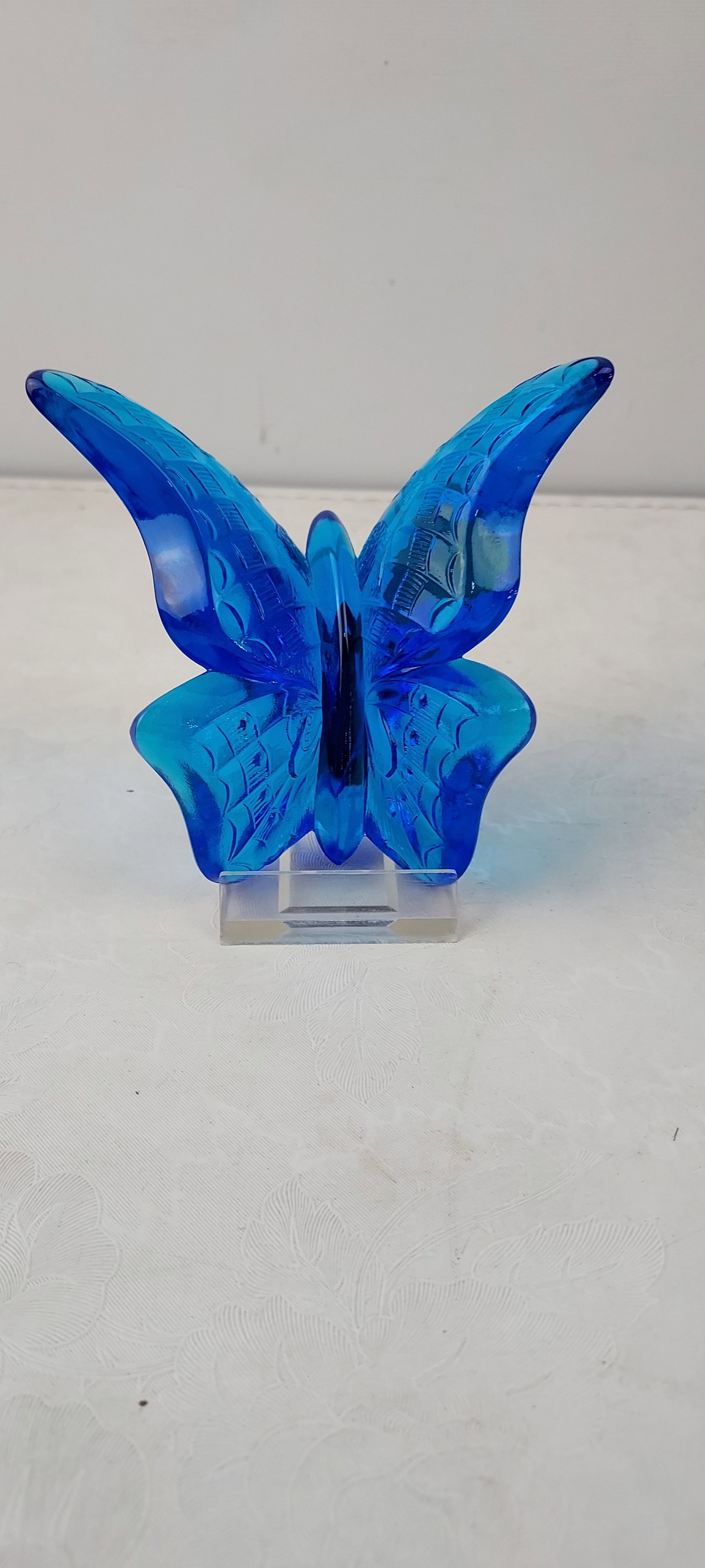 Vintage Fenton Art Glass Colonial Blue Butterfly Figurine: A vintage Fenton Art Glass butterfly figurine, crafted from translucent colonial blue glass. This piece features intricate molded details on its wings and body, characteristic of Fenton's hand-made gl