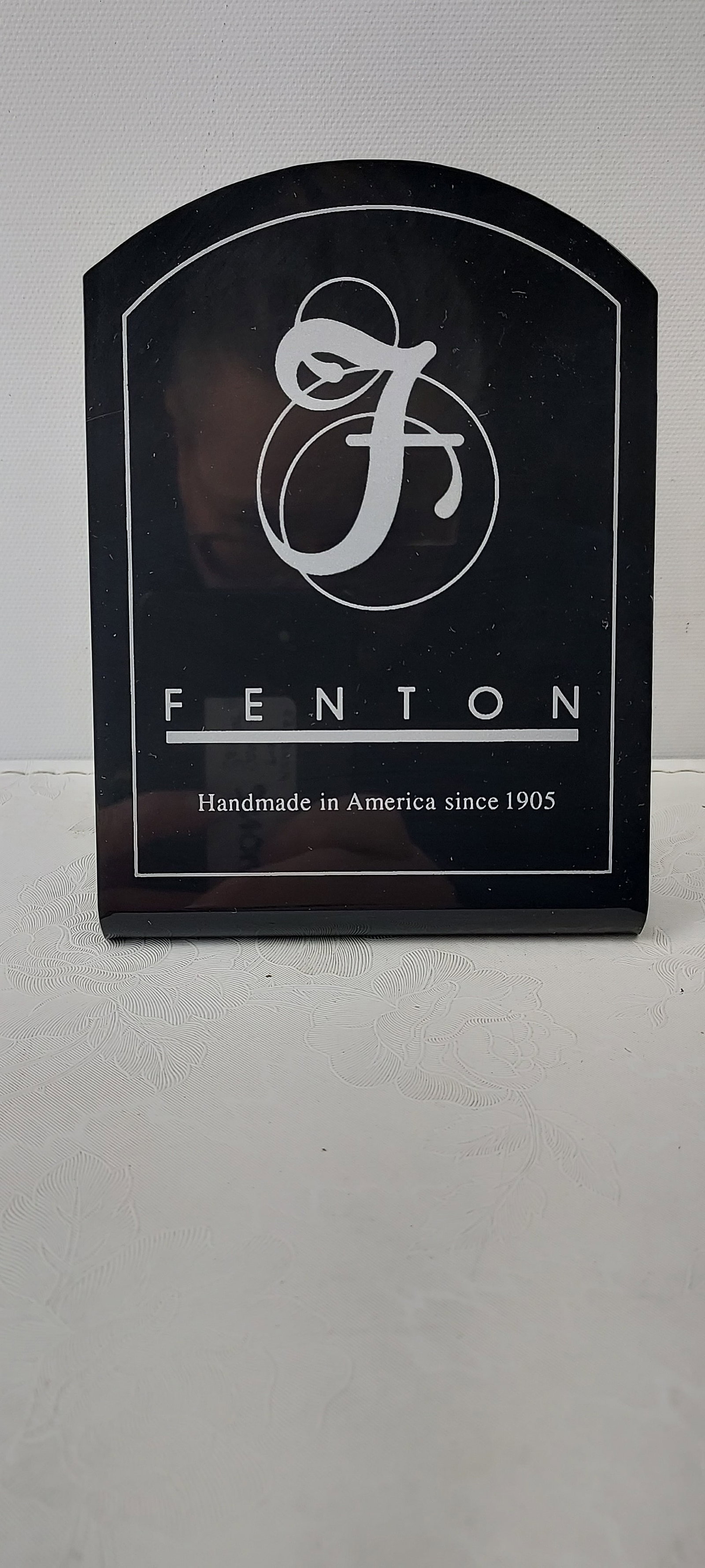 Fenton Art Glass Dealer Logo Display Sign, Black Plastic Arched-Top: This is a Fenton Art Glass Dealer Logo Display Sign, a black, arched-top display plaque. It is constructed from acrylic or a similar rigid, glossy black material. The front prominently features the ic