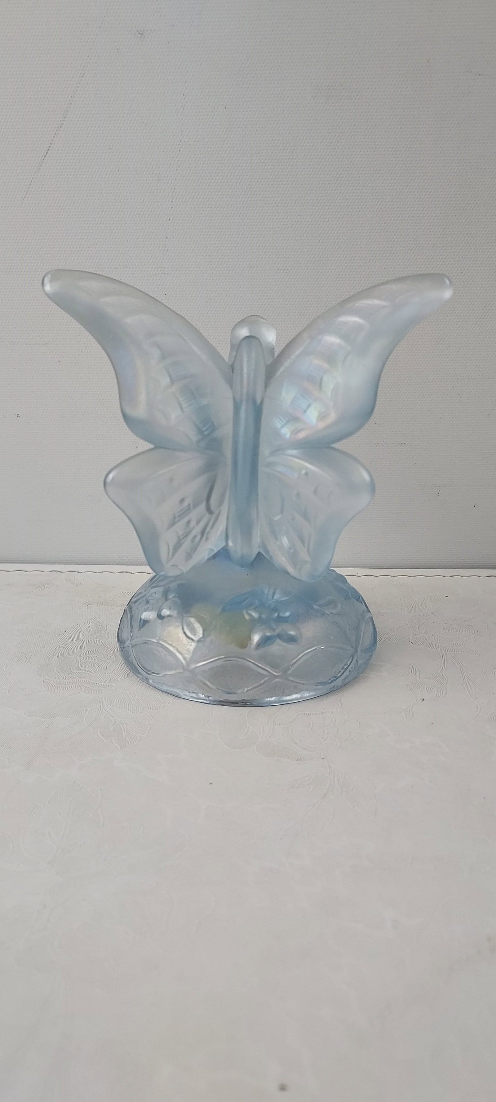 Fenton Art Glass Iridescent Ice Blue Butterfly on Branch Ring Holder: This listing features an authentic Fenton Art Glass Iridescent Ice Blue Butterfly on Branch Ring Holder. The loose figurine is crafted from light blue frosted or satin glass, depicting a butterfly per