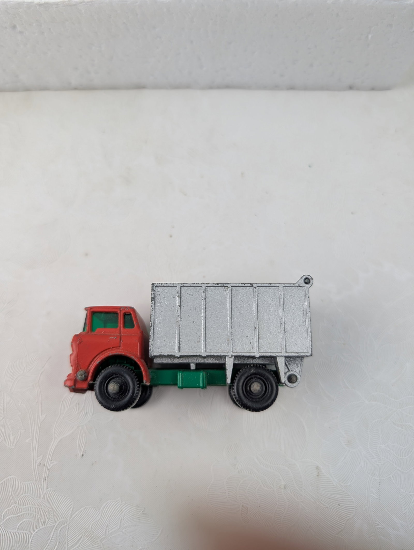 Vintage Lesney Matchbox Series No. 25 G.M.C. Tipper Truck: This is a vintage Lesney Matchbox Series No. 25 G.M.C. Tipper Truck, manufactured in England by Lesney. This die-cast toy truck features a red cab with tinted green plastic windows, a green chassis, a