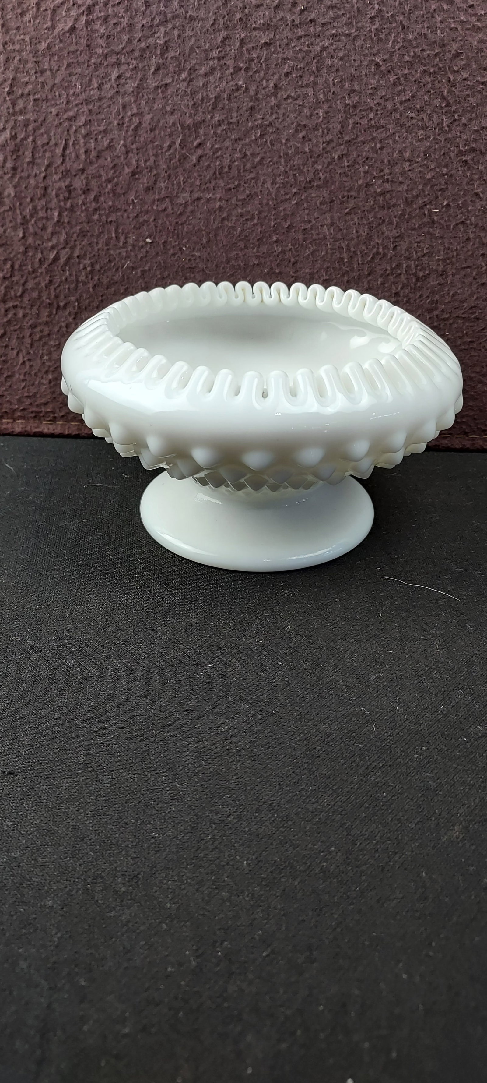 Vintage White Milk Glass Hobnail Ruffled Rim Footed Bowl / Candle Holder: This vintage footed bowl, crafted from opaque white milk glass, features a distinctive hobnail pattern of raised bumps covering its exterior surface. The rim is elegantly ruffled or crimped, often ref