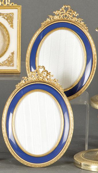 Pair of bronze oval tabletop picture frames with blue: Pair of oval tabletop picture frames in gilt bronze and blue enamel, Louis XVI style, France 19th century. With bow and flower pompadour. Size:: 19 x 13.5 cms.