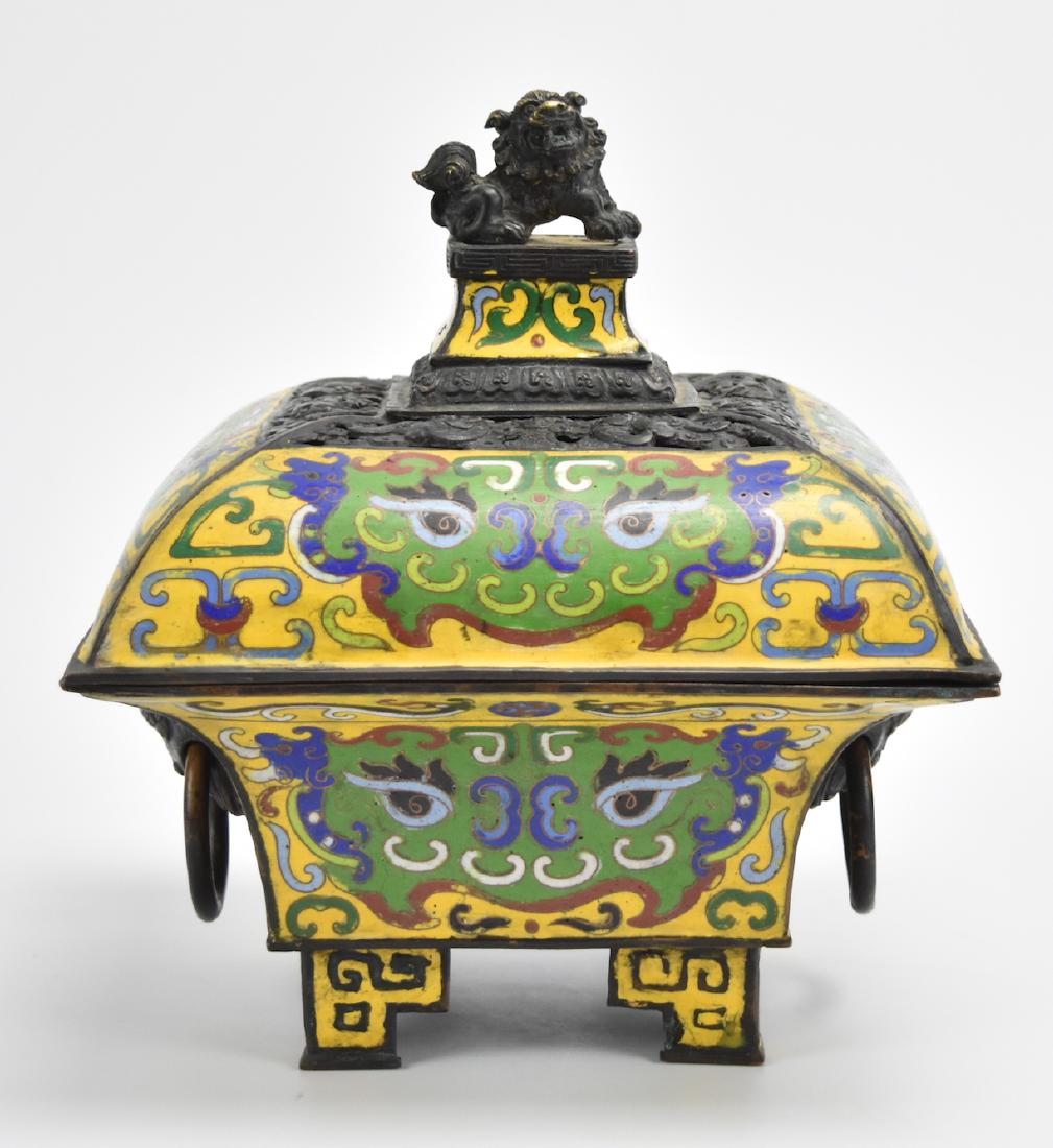 A Chinese Bronze Enamel Censer: A lantern shaped, four-sided, bronze censer with tall terraced feet, free hanging hoop handles suspended by Foo-dog/ guardian-lion faces, with a further Foo-dog finial on a raised platform surrounded 