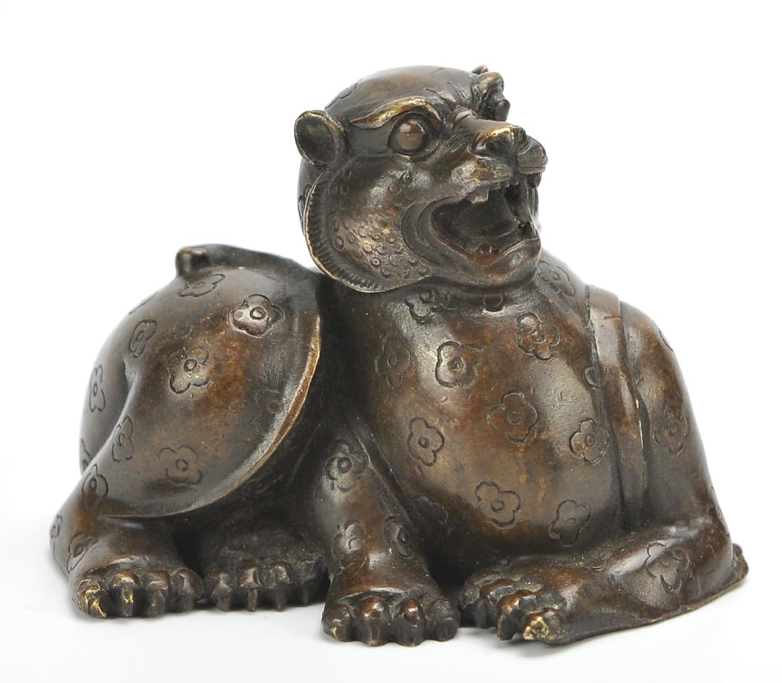Chinese Reclining Bronze Foo-Dog/ Shisa: A small bronze "Foo-dog/ Shisa", mouth agape, with prominent claws and tail, beginning to rise from a reclining posture. W: 4" (10.2cm) Condition: in good condition with age related wear