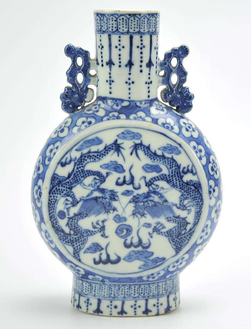 Chinese Blue& White Dragon Moon Flask Vase,19th C.: A blue & white, Chinese, porcelain moon flask with panel illustrations featuring twin dragons, in mirror image of one another, chasing after a flaming pearl surrounded by white blossoms on a blue back