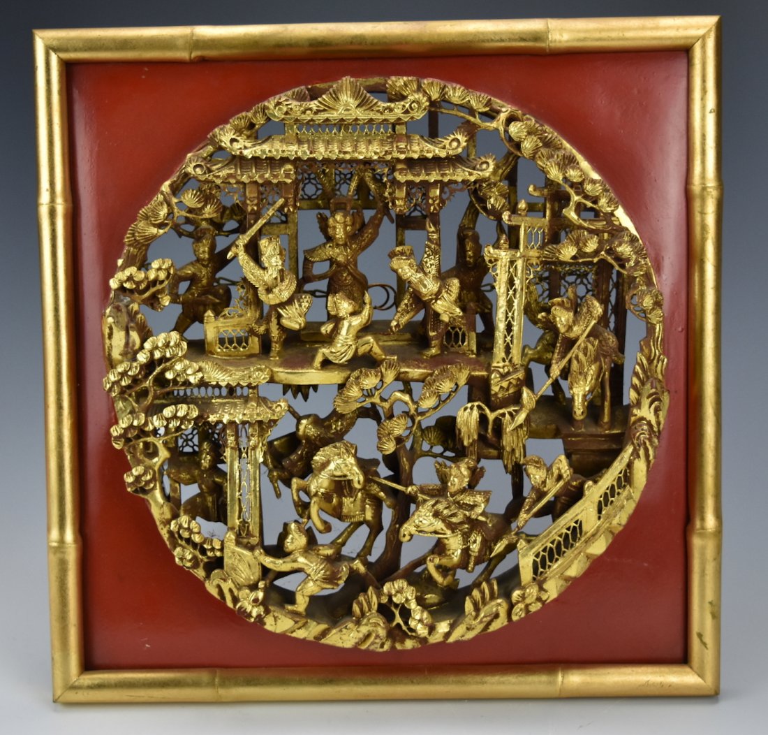 A Chinese Gilt Wood "Battle" Plaque,20th C.: A disc shaped wooden plaque, gilded, and carved in high-relief from a single piece of wood depicting figures wielding spears and swords, on foot & on horseback, battling in a two story complex with sw