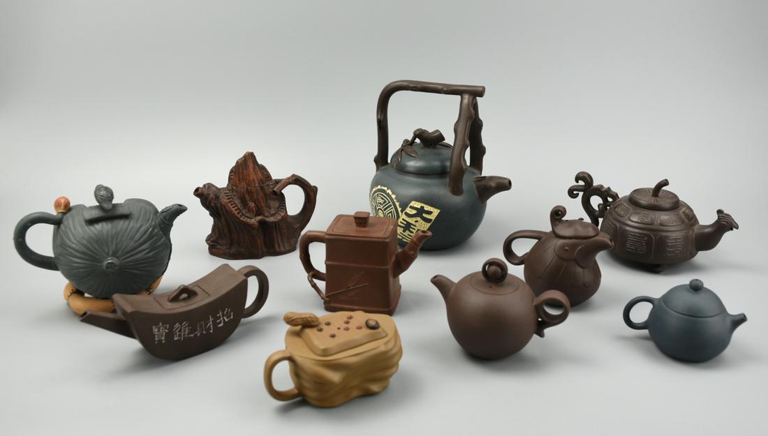 (10) Decorative Chinese Zisha Teapots: A lot of 10 decorative, Chinese, earthenware teapots: - Green, globular, with characters& a wheel inscribed in white, with dark-brown bamboo styled handles and spout. H: 6 7/16" (16.4cm) - Tan, small