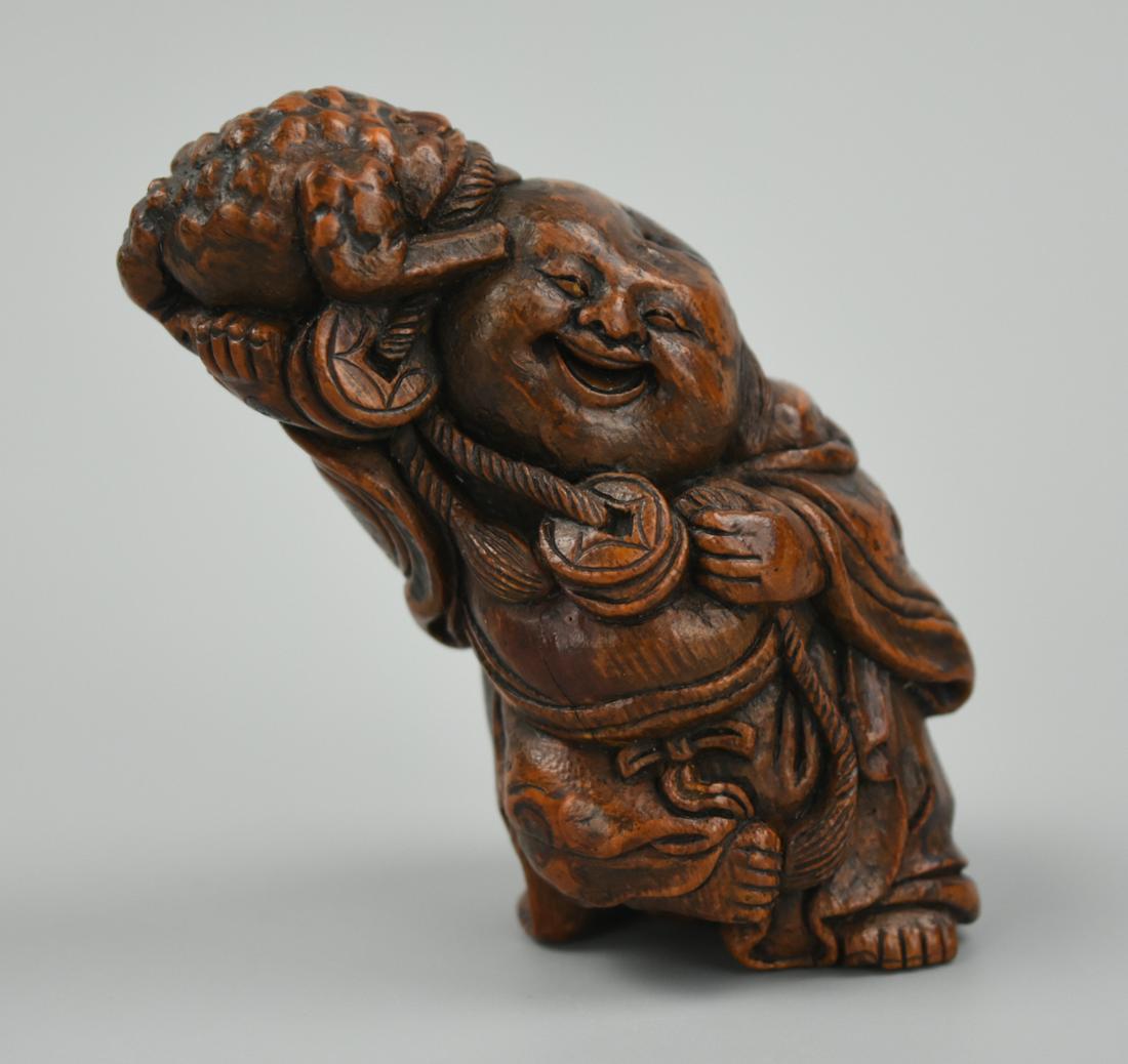 Small Chinese Wooden Bamboo Figure of Buddha: A small, well carved, wooden figure as a seated Budai, the laughing Buddha wearing loose robes draped over his corpulent body, his chest and large stomach bare, his left hand carved holding a lion mas