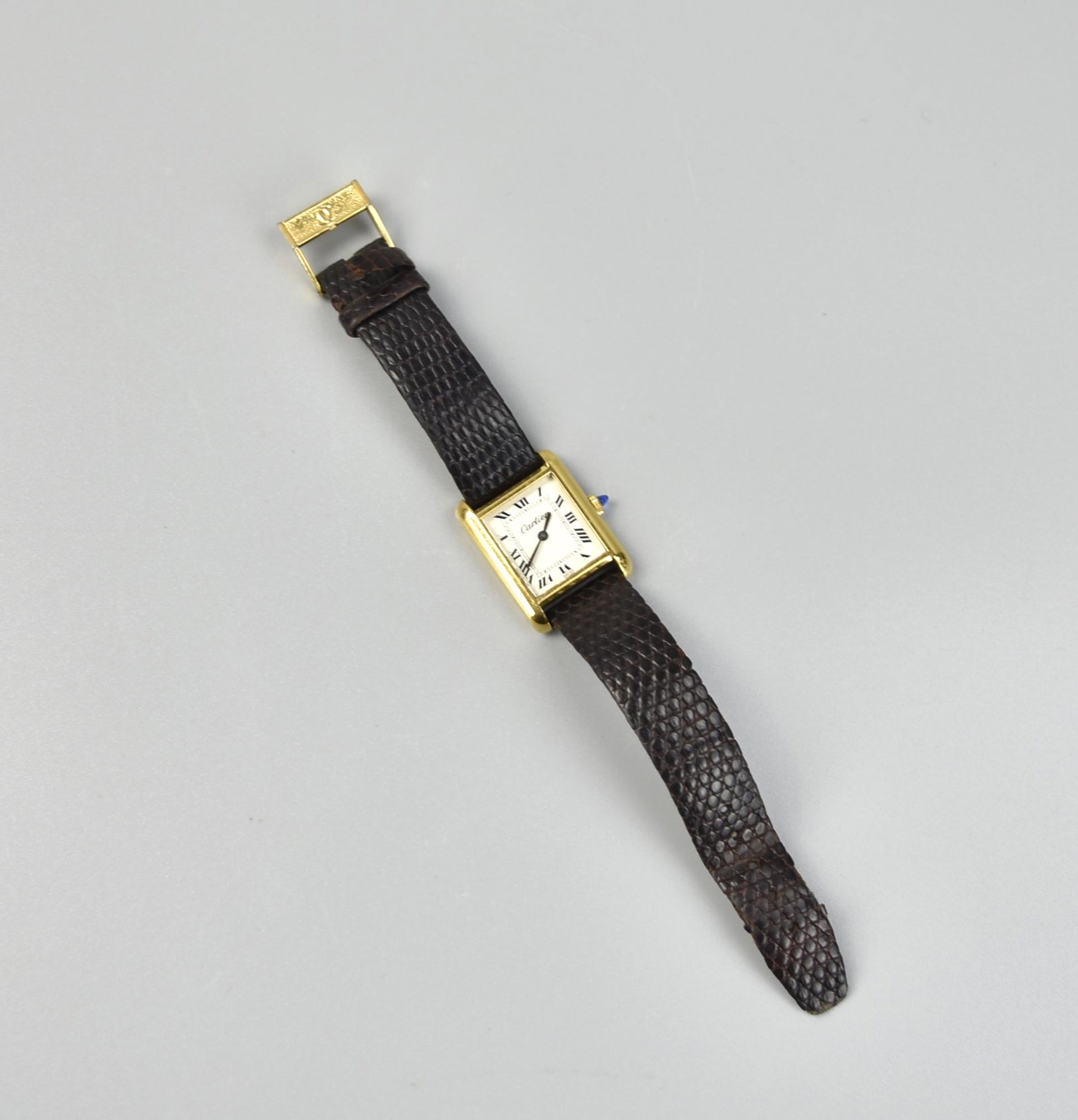 Cartier, 18K Carat Gold Women Watch: a rectangular shaped watch, with 18K Carat Gold frame with buckles, and brown leather strips L: 7"(17.8cm) Condition: one band on the leather strip is broken, otherwise is in good condition