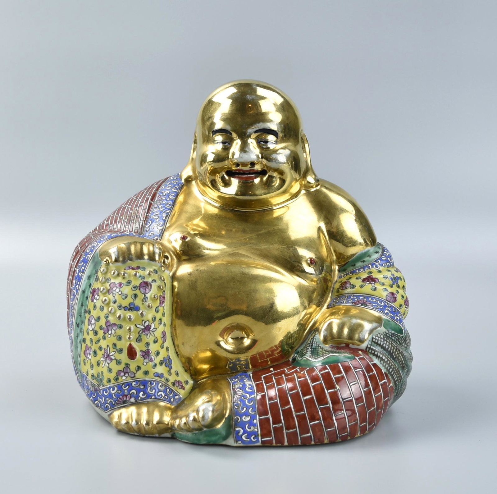 Chinese Gilt Famille Rose Buddha Statue,ROC Period: A Chinese,ROC Period, porcelain figure of buddha, seated with one hand place on his knee, the other hand holding a beeds bracelet, opened mouth, mirthful expression, decorated with colorful robs on a 
