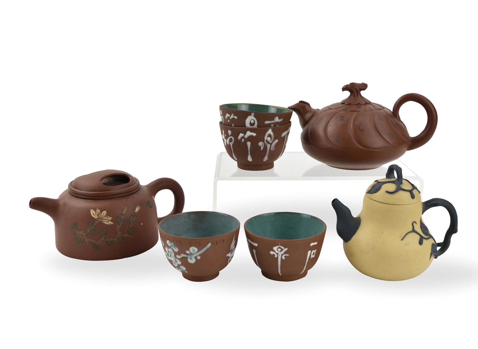 A Group of (3) Chinese Zisha Teapot and (4) Cups: brown zisha teapot in globular form with loop handle & a bird head-like finial with a long beak on the lid teapot of pear shaped form with raised leaf on the body and lid, the spout, rear, & top handl