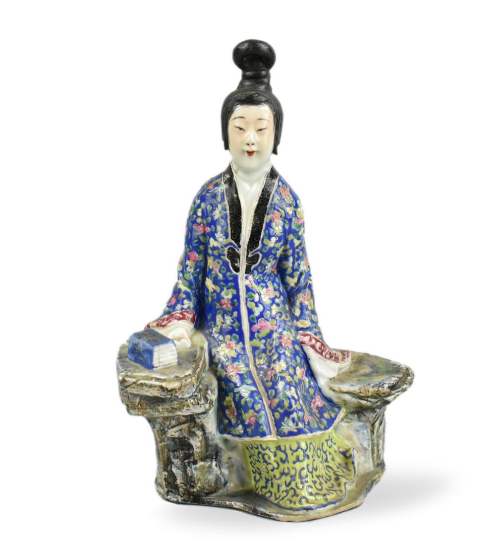 Chinese Famille Rose Porcelain Figure, ROC Period: A Chinese famille rose porcelain figure, dating from the Republic period. A woman in a colorful robe with pink and white flowers against a blue background is seated on a curved rock, the rock painted 