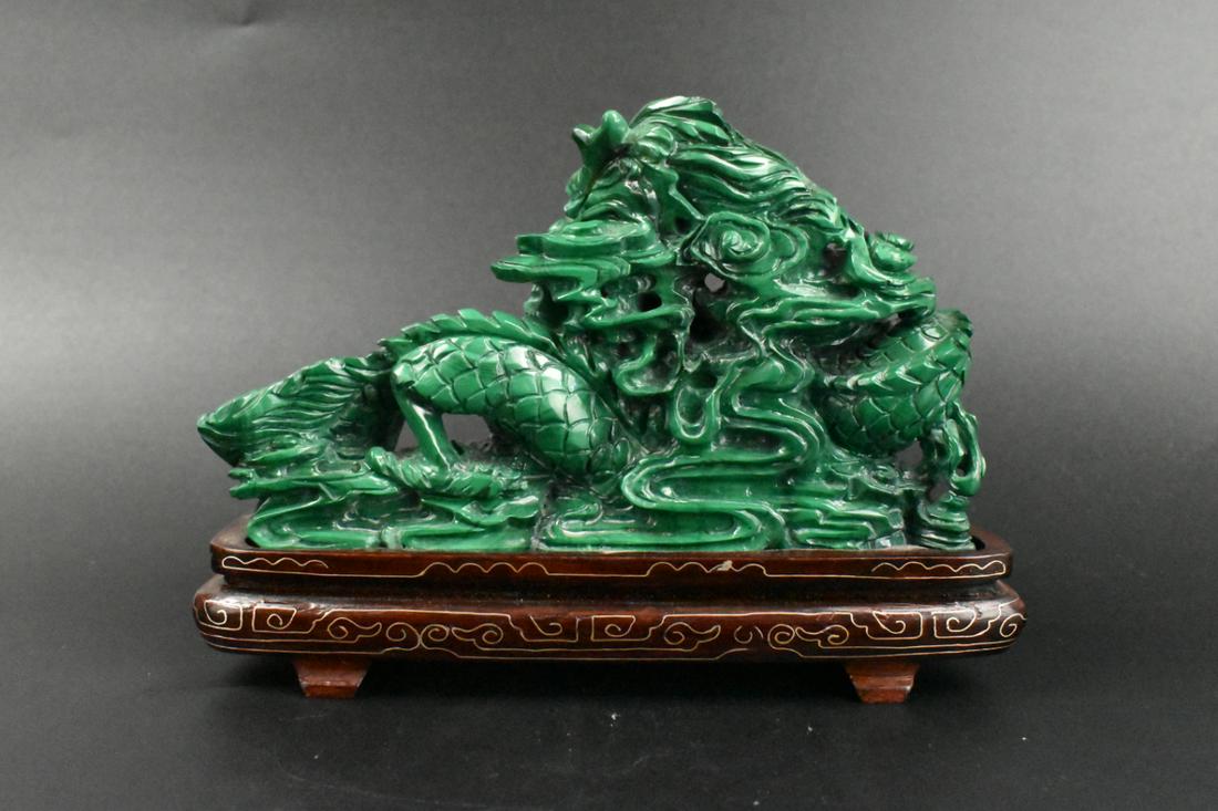 Chinese Malachite Carved Dragon & Cloud on Stand: A Chinese malachite carved dragon and cloud on custom wooden stand. A fierce dragon coiled with scales among waves. The dragon turns its head over its body, showing its teeth. The stand had lines of d