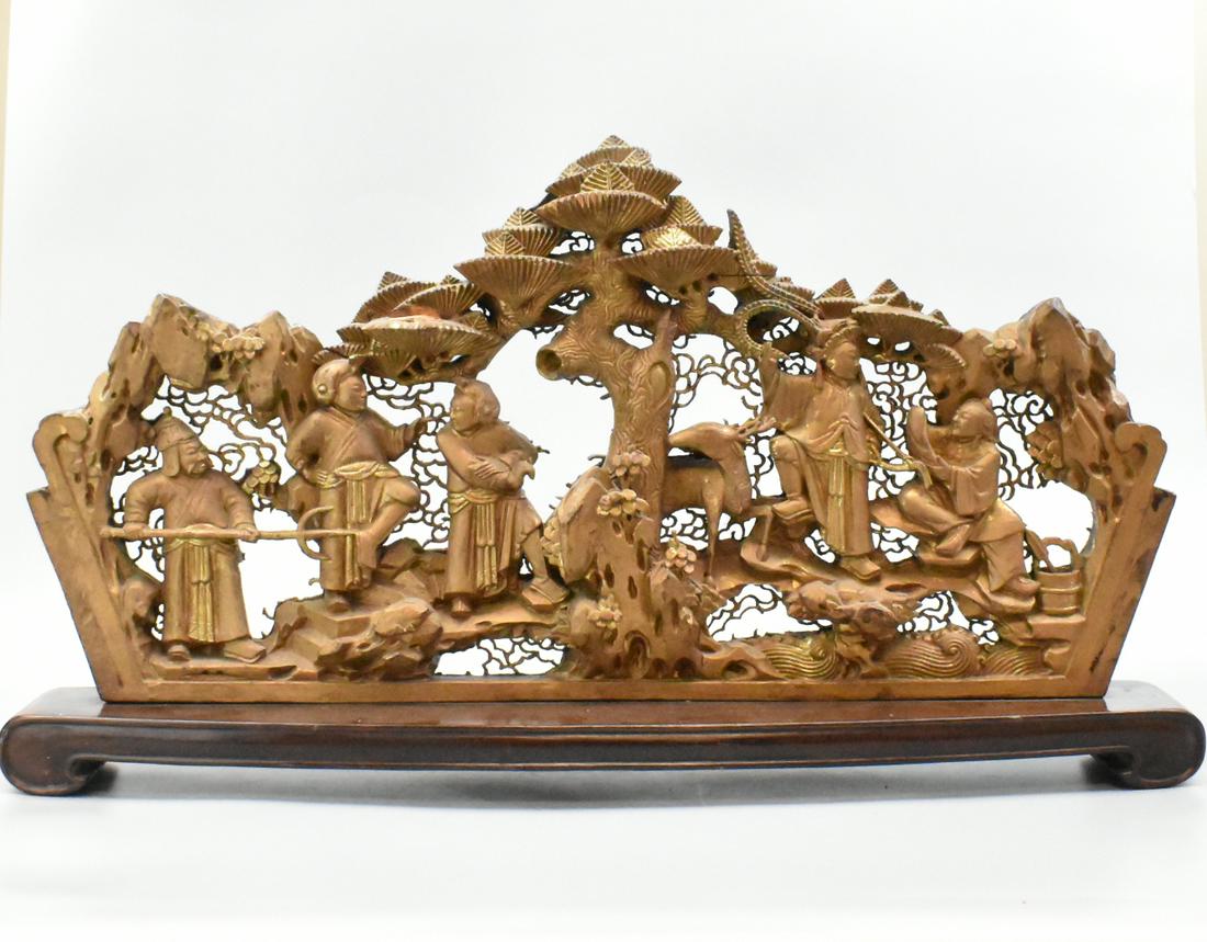 Large Chinese Gilt Wood Carving Panel,Qing Dynasty: A large Chinese gilt wood carved panel. Surrounding a central carved tree and deer are five figures carved in deep relief, all gesturing in an animated composition. Mounted on a wooden stand with scro