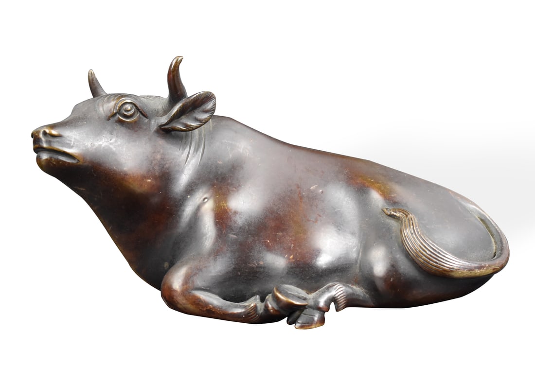Chinese Bronze Cast Water Buffalo, Qing Dynasty: A Chinese bronze cast water buffalo, dating from the Qing dynasty. The water buffalo is seated with its head looking to its left. The long, angular spine leads to a tail that's curled around the backs