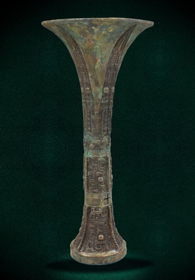 Chinese Bronze Ritual Wine Vessel Gu,Shang Dynasty: A Chinese bronze ritual wine Gu vessel dating from the Shang dynasty. With a trumpet rim over the slender neck, decorated with four elongated blades crisply cast Taotie motif in relief. With a rich, m