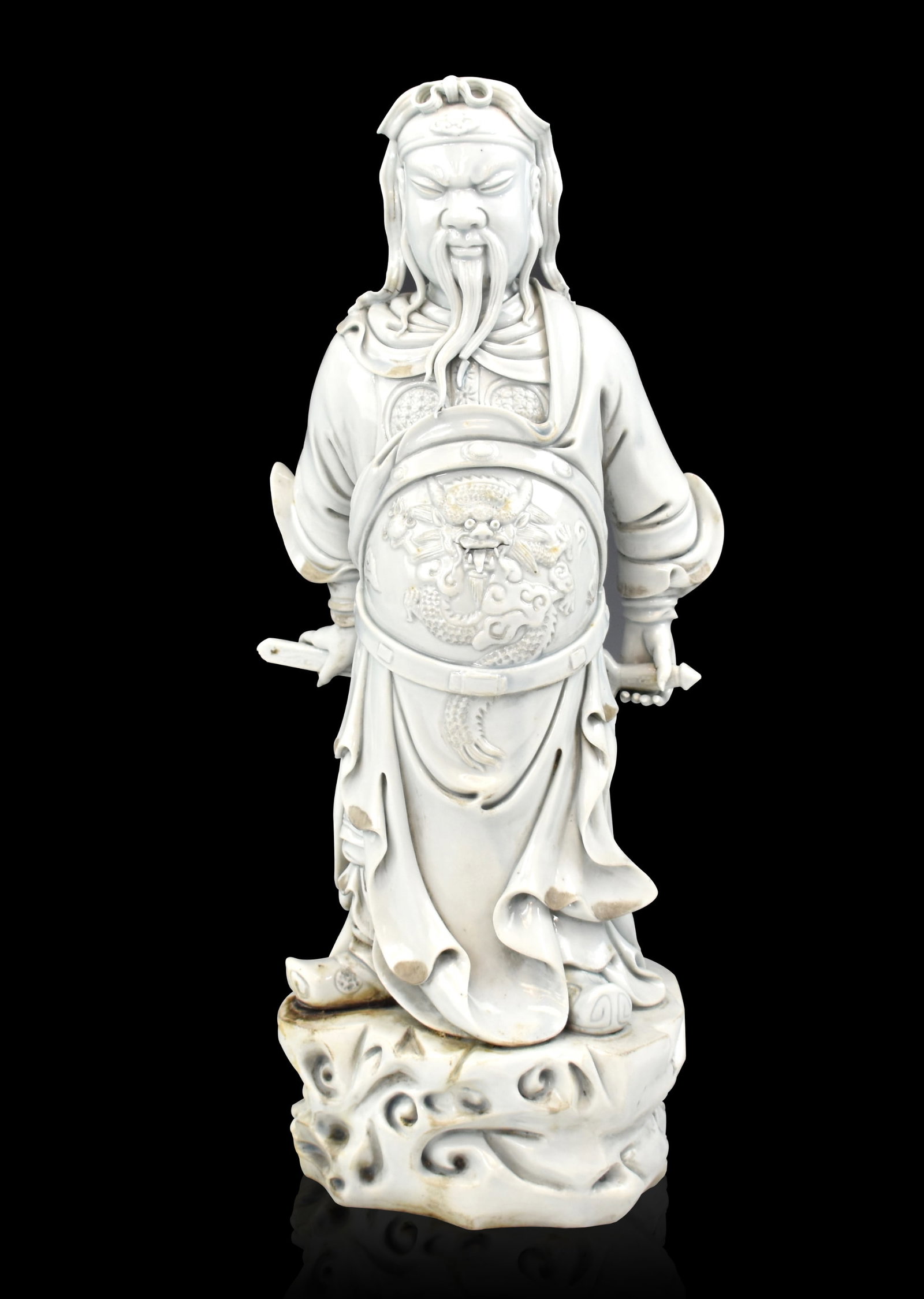 Chinese Blanc De Chine Figure of Guan Gong,20th C.: A Chinese blanc de chine figure of Guan Gong,dated to 20th C, the general stands fiercely on a pedestal with dragon armor body covering and holds a sword behind him with both hands. He has a stern exp