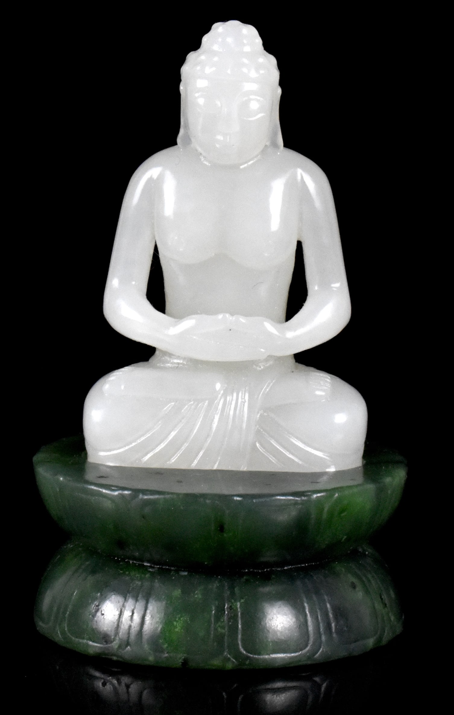 Chinese White Jade Carved Buddha on Lotus Base: A Chinese white jade carved Buddha figure on spinach jade stand. The small and serene Buddha is seated in meditation pose with both hands joined in front, the head slightly bowed. On a two tier rounde