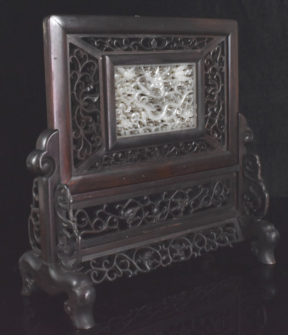 Chinese Table Screen w/ Jade Carved Dragon Plaque: A Chinese table screen with Jade carved dragon plaque. Openwork dragon plaque with detailed curving dragon amongst foliage design, set within detailed scrollwork wooden panel insert into a wooden stan