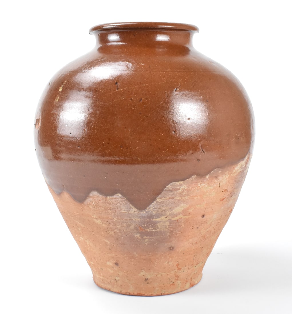 Chinese Straw Glazed Jar ,Tang Dynasty: A Chinese straw glazed jar dating from the Tang dynasty (618-907). A heavily potted stoneware jar that tapers from a wide shoulder to the splayed foot. Short neck and thick rounded rim. Straw glaze ap