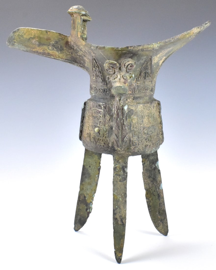 Chinese Archaic Bronze Ritual Vessel"Jue",Shang D.: A Chinese archaic bronze ritual vessel "Jue" dating from the Shang dynasty (1600-1045 BC), the U shaped body rising from three splayed triangular blade legs to a pointed rim opposite a guttered spout 