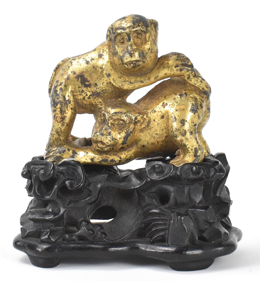 Chinese Gilt Bronze Monkeys on Stand, Qing Dynasty: A Chinese gilt bronze of monkeys on a wooden stand, dating from the Qing dynasty. The two monkeys are being playful with one grabbing the others legs at the other grabs that one's tail. On a tall reti