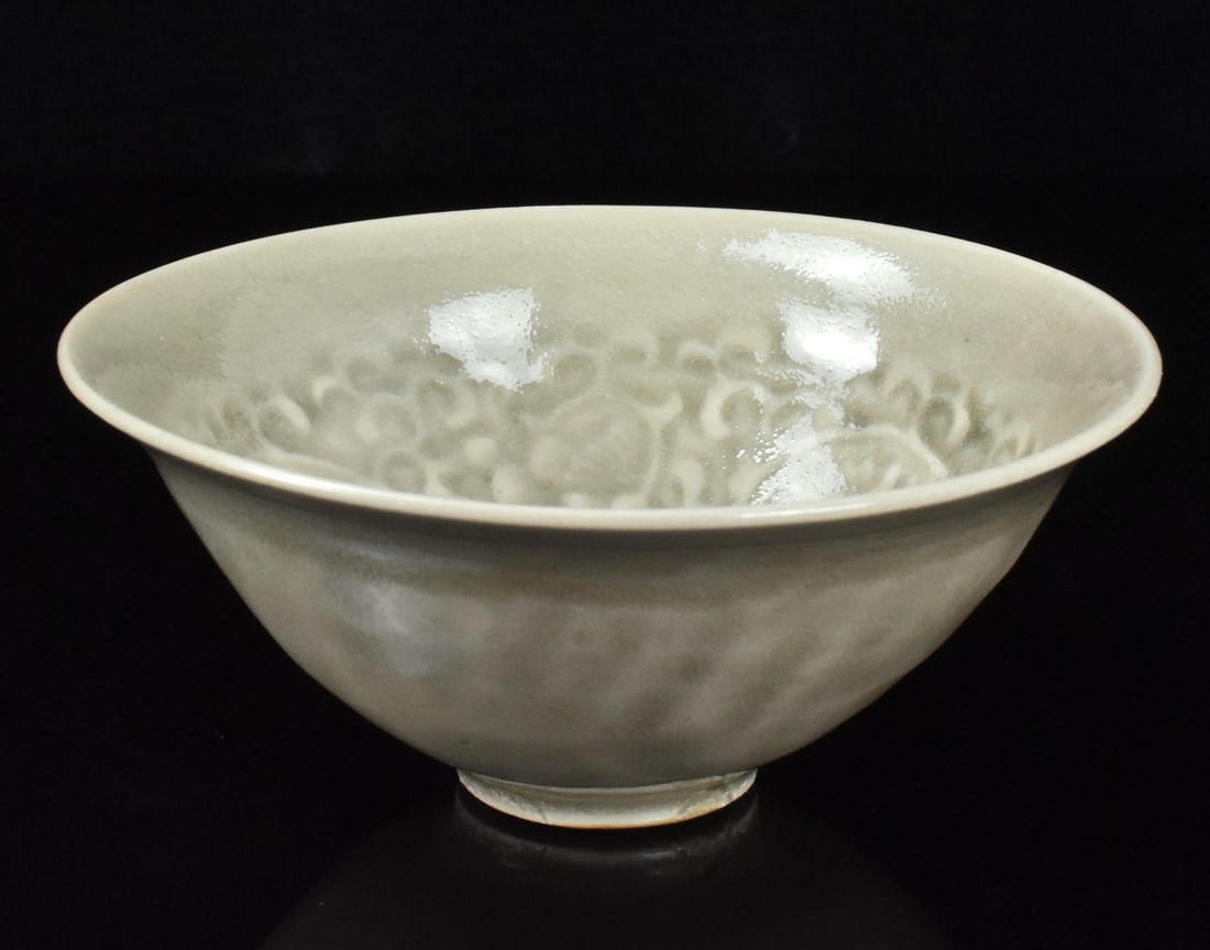 Chinese Yaozhou Chrysanthemum Bowl,Song D.: A Chinese Yaozhou Chrysanthemum bowl dating form the Song dynasty (960-1279). of conical form with a slightly everted rim, the interior impressed with chrysanthemum scrolls, applied overall with an ol
