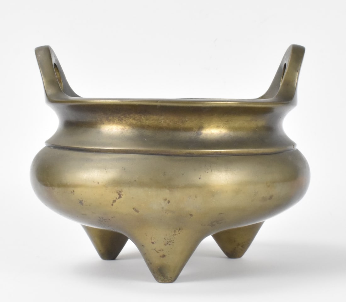 Chinese Bronze Cast Tripod Censer, Qing Dynasty: A Chinese bronze cast tripod censer, dating from the Qing dynasty. Over three triangular feet, a censer with compressed body to a curved neck and flat rim. Rim has two rounded handles at the sides. Wi