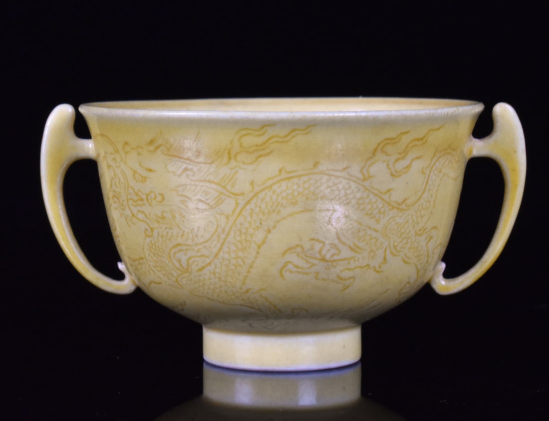 Chinese Yellow Glazed Dragon Cup, Qing Dynasty: A Chinese yellow glazed dragon cup, dating from the Qing dynasty. Interior yellow glaze with exterior incised dragon chasing flaming pearl on both side. With two delicate, ornate handles and crisp six