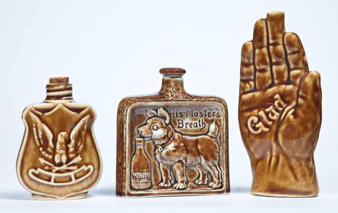 THREE FIGURAL FLASKS: German, late 19th-early 20th century. Includes a "Glad" hand, 6" long; an eagle flask, 3.75" high; and a satirical "His Master's Breath" flask, 3.75" high.