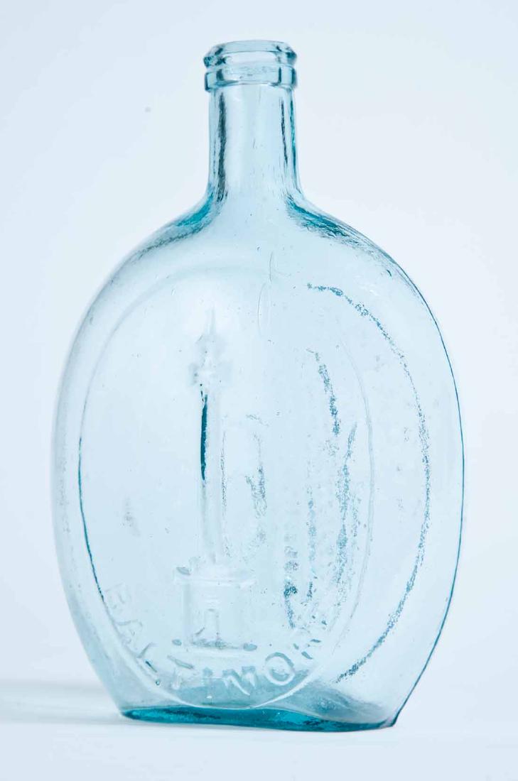BALTIMORE MONUMENT FLASK: GVI-4, Baltimore Glass Works, mid-19th century, quart, aqua in color, Washington Monument and "BALTIMORE" on the obverse and an ear of corn and "CORN FOR THE WORLD" on the reverse. Beveled lip and pla