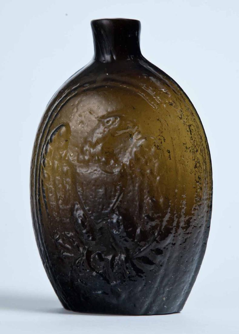 EAGLE & CORNUCOPIA FLASK: GII-72, possibly Keene-Marlboro-Street Glass Works, Keene, NH, mid-19th century, pint, olive-amber in color, with a eagle on rocks on the obverse and a large cornucopia on the reverse, and a plain lip