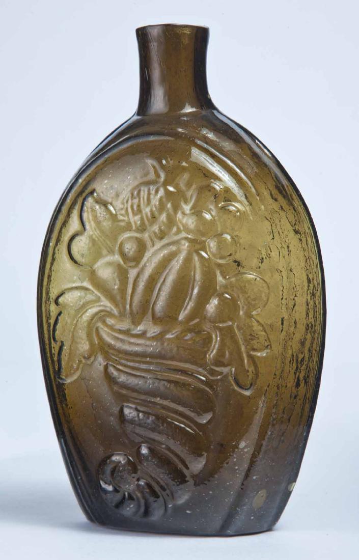CORNUCOPIA FLASK: GIII-4, Coventry Glass Works, Coventry, CT, mid-19th century, pint, olive-amber in color, with a cornucopia (with pineapple) on the obverse and an urn on the reverse, plain lip and pontil mark. 7" hig