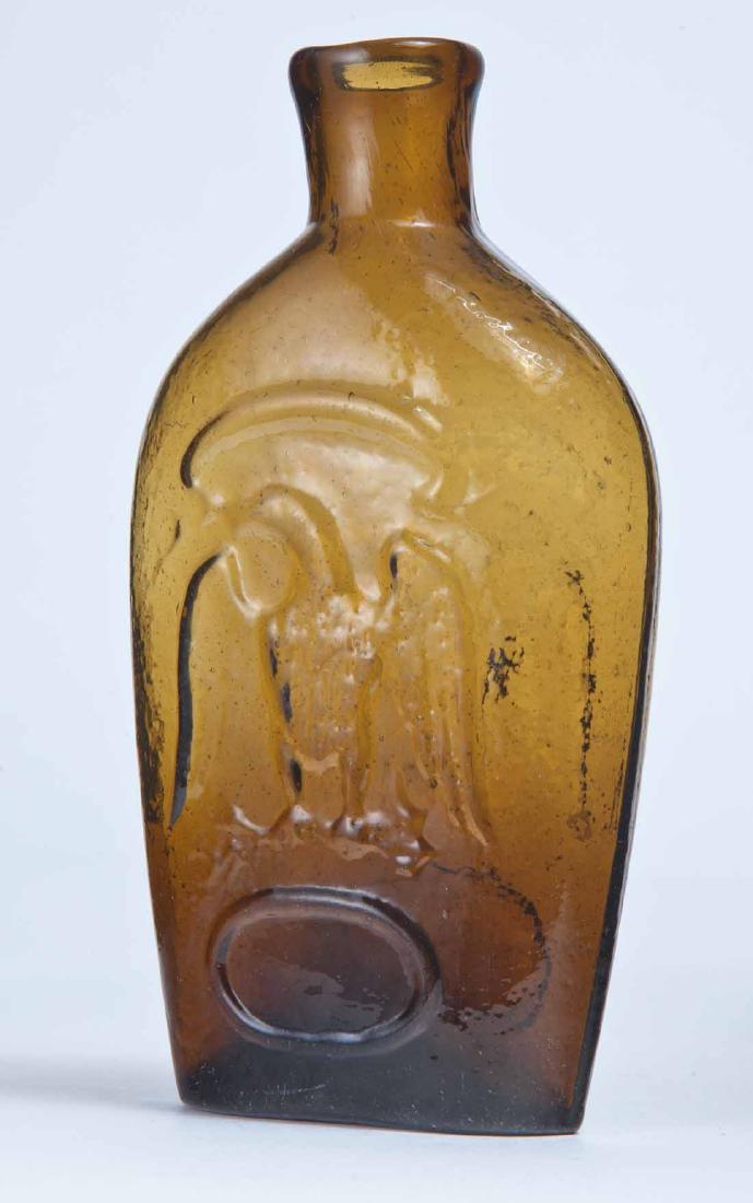 DOUBLE EAGLE FLASK: GII-86, New England, possibly Granite Glass Works, mid-19th century, amber in color, both sides with eagles over blank frames, plain lip and pontil mark. 6" high.