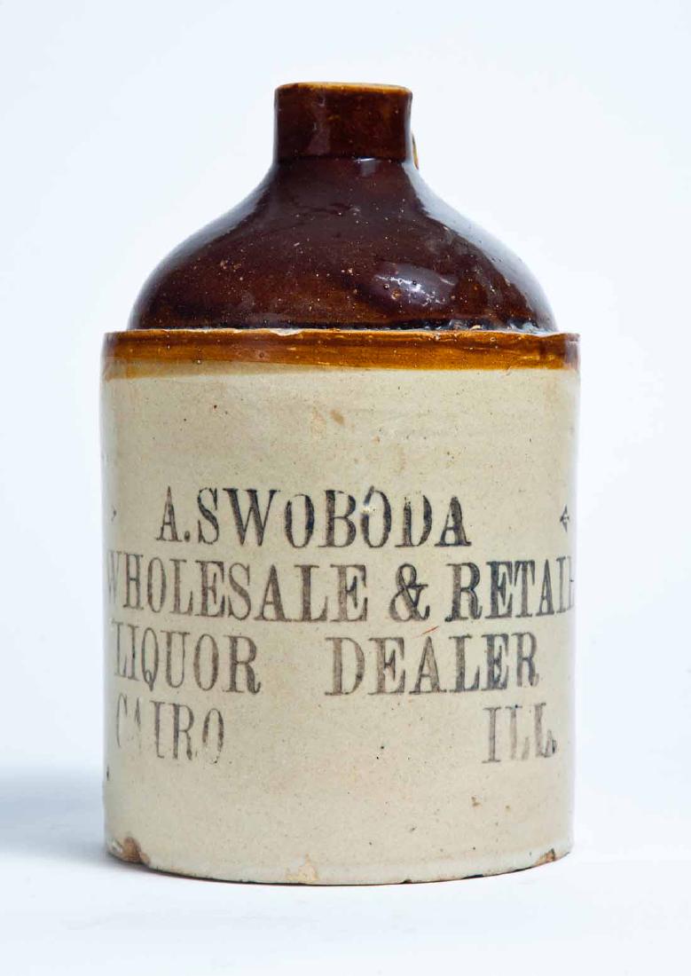 CAIRO, ILLINOIS ADVERTISING STONEWARE LIQUOR JUG: Half-gallon jug with bicolor glaze and stamped advertisement "A. SWOBODA WHOLESALE & RETAIL LIQUOR DEALER CAIRO ILL." 8.5" high.