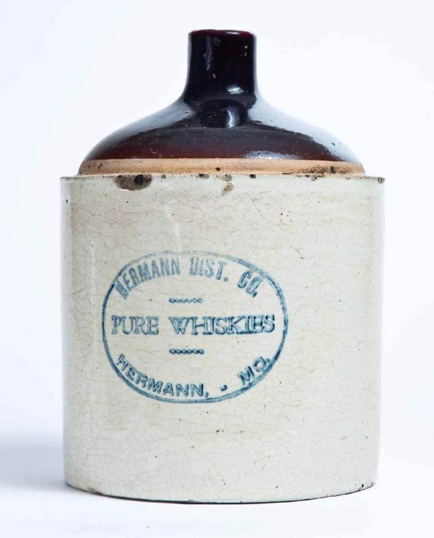 HERMANN, MISSOURI ADVERTISING STONEWARE WHISKEY JUG: 1-gallon jug with bicolor glaze and stamped advertisement "HERMANN DIST. CO. PURE WHISKIES HERMANN, MO." 10" high.