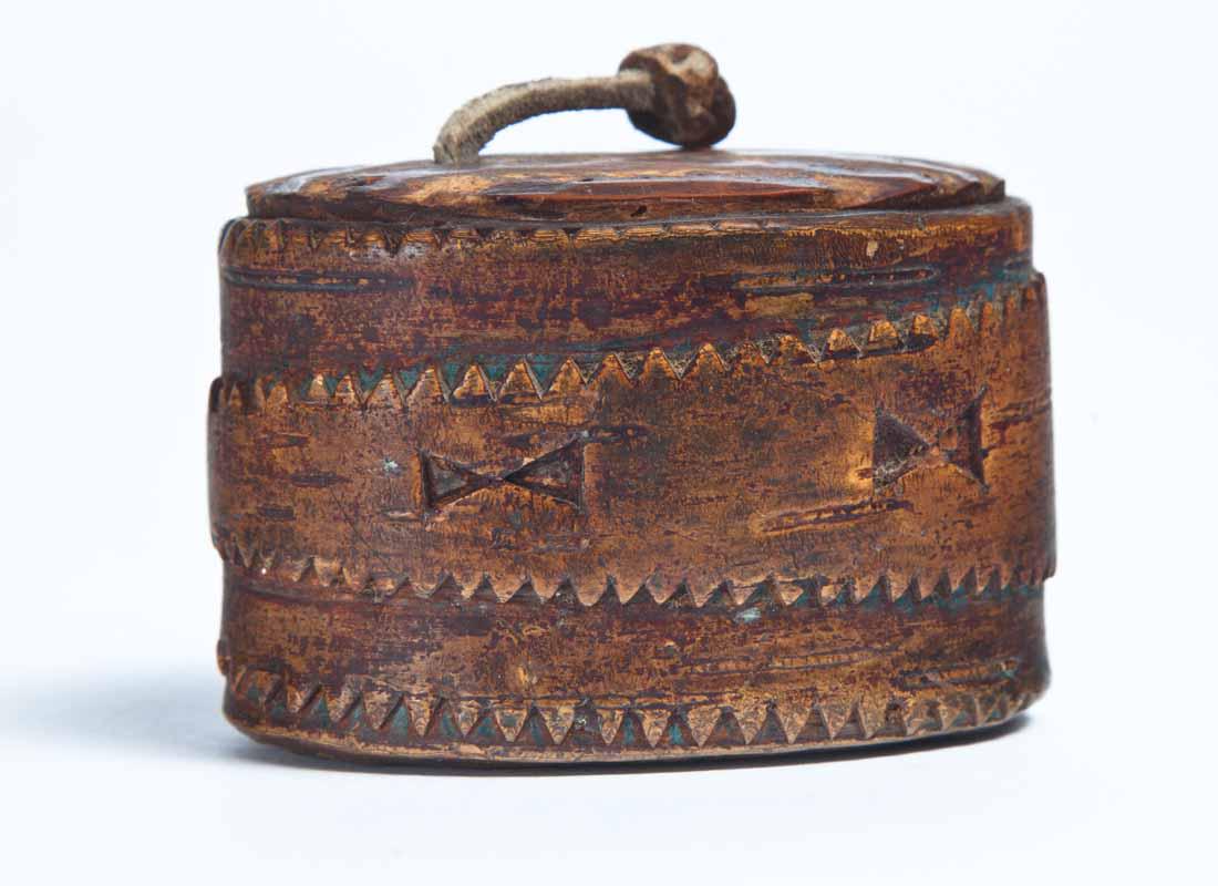 CARVED WOOD SNUFF BOX: Oval wrap-around design with geometric and sawtooth carvings. Knotted leather thong lid handle. Ex-Knittle Collection, purchased from Garth's Auctions, November 1962. 1.75"h. 2"l. 1.75"w.
